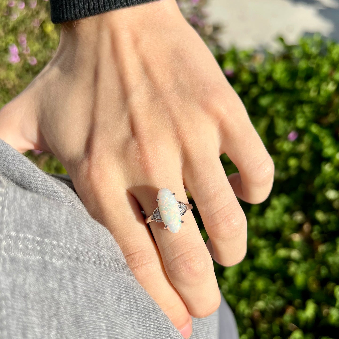 A Coober Pedy white opal platinum ring set with diamond accents.  The opal plays soft pink colors.