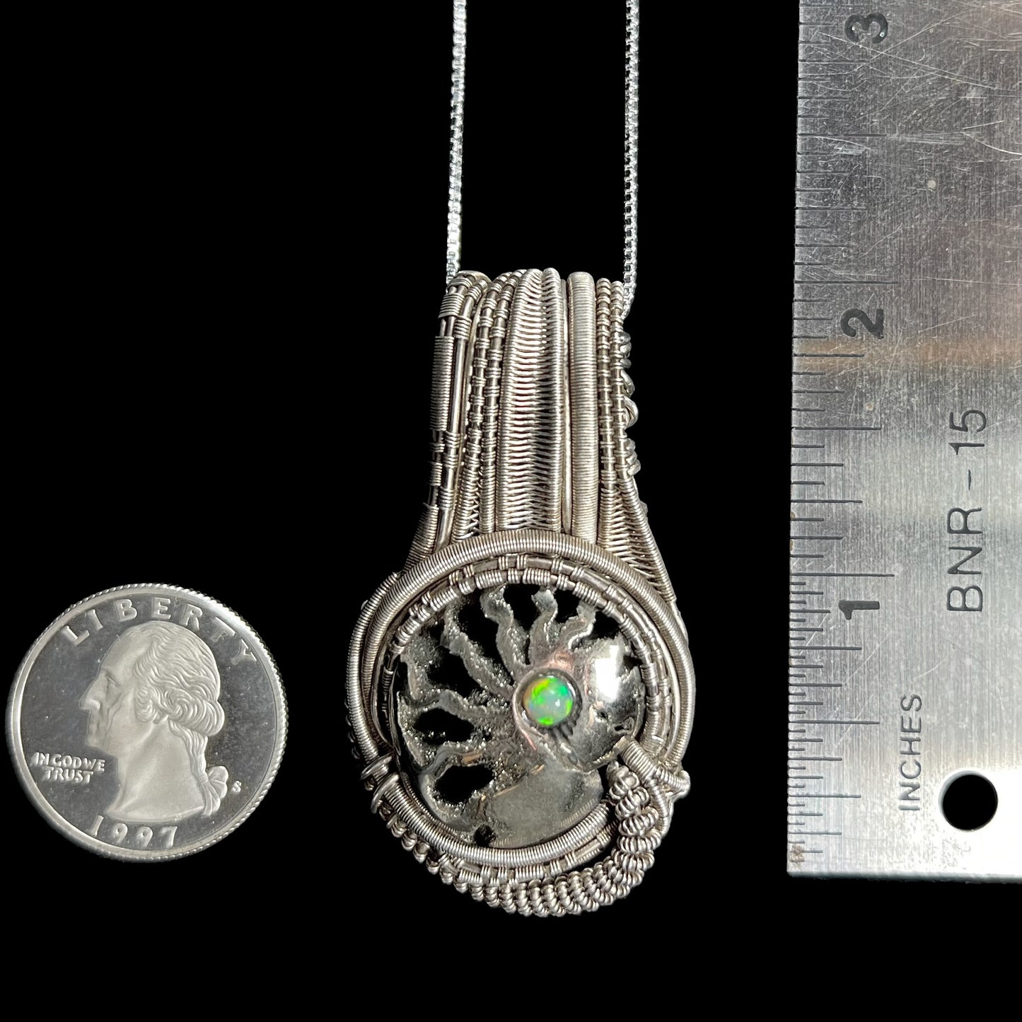 2 inch-long wire wrapped ammonite and Ethiopian opal pendant shown between US quarter coin and ruler for scale.
