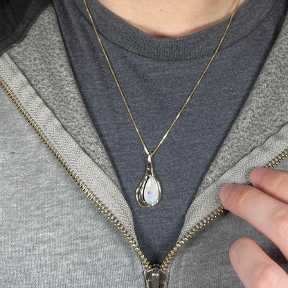 Close-up of person's neck and chest wearing 14k gold Modernist style opal women's necklace against dark shirt