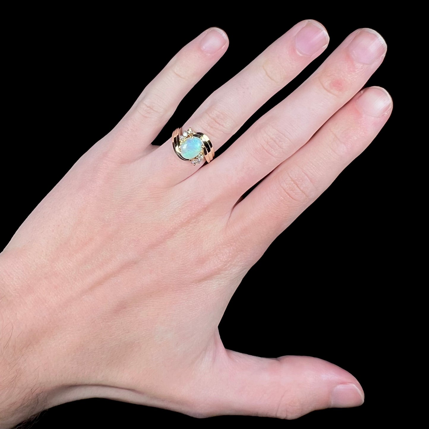 Hand wearing women's 1980s-era Modernist Australian opal and diamond ring in 14k gold