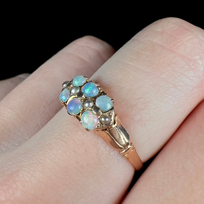 Angled close-up of women's 9k gold opal and pearl ring, worn on finger under LED studio light