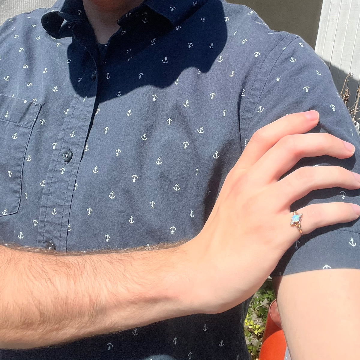 Close-up of person resting hand on opposing shoulder in sunlight wearing a women's antique opal and diamond pinky ring