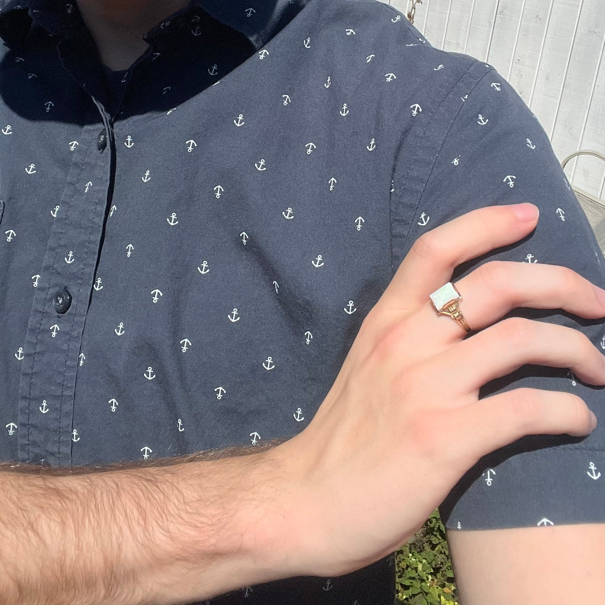 Close-up of person resting hand on opposing shoulder in sunlight wearing a women's Art Deco opal solitaire ring