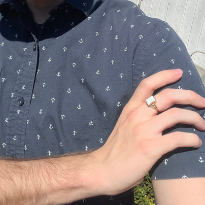 Close-up of person resting hand on opposing shoulder in sunlight wearing a women's Art Deco opal solitaire ring