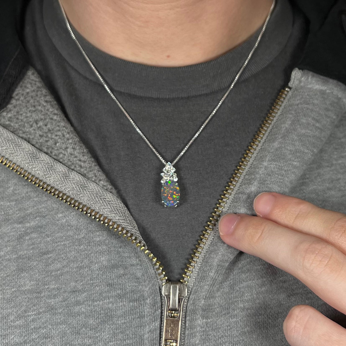 Close-up of a person's neck and chest wearing a multicolor Australian black opal and diamond women's necklace.