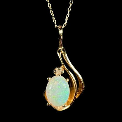Close-up of a women's dainty 14k gold Australian opal and diamond pendant with asymmetrical design shown on 14k gold chain