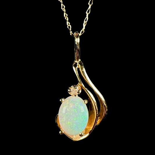 Close-up of a women's dainty 14k gold Australian opal and diamond pendant with asymmetrical design shown on 14k gold chain