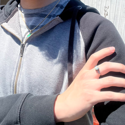 Close-up of person resting hand on opposing shoulder wearing women's black rhodium plated opal ring