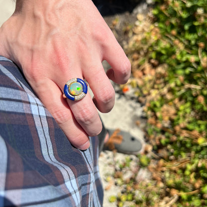 Hand resting on person's hip while wearing a Cirari designer Ethiopian opal women's ring with a lapis lazuli and diamond halo ring in natural sunlight.