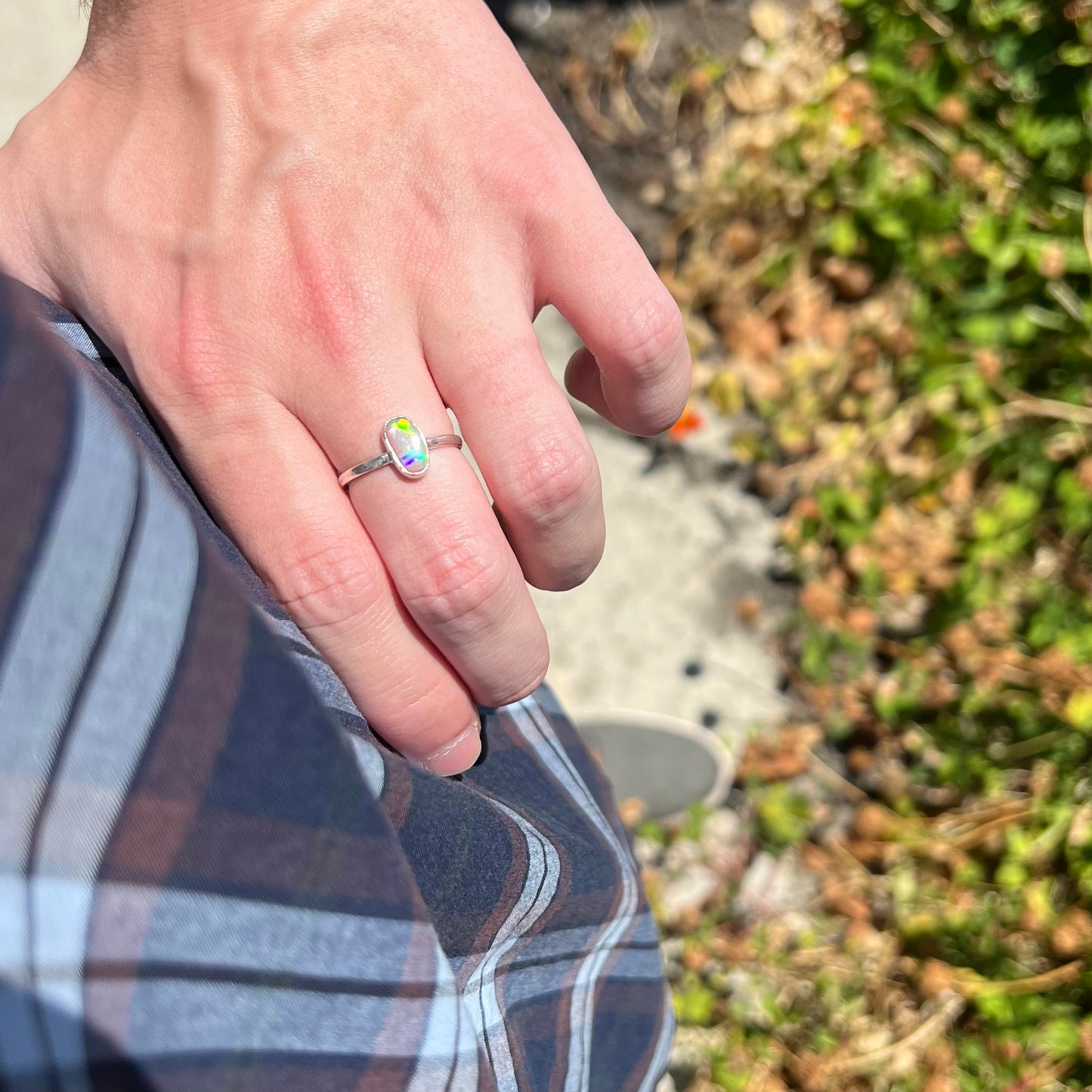 Person's hand resting on their hip in natural light while wearing women's crystal opal solitaire ring.