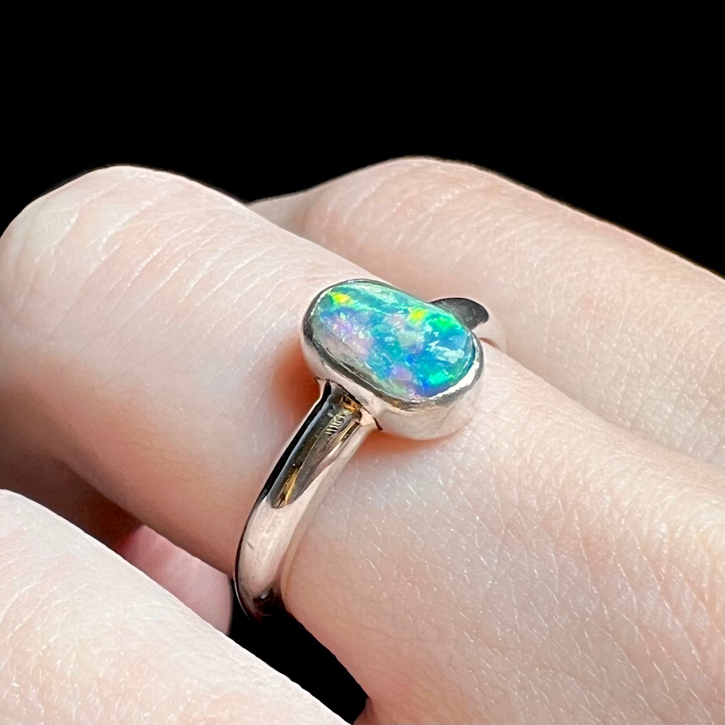 Angled close-up of women's crystal opal solitaire ring in silver