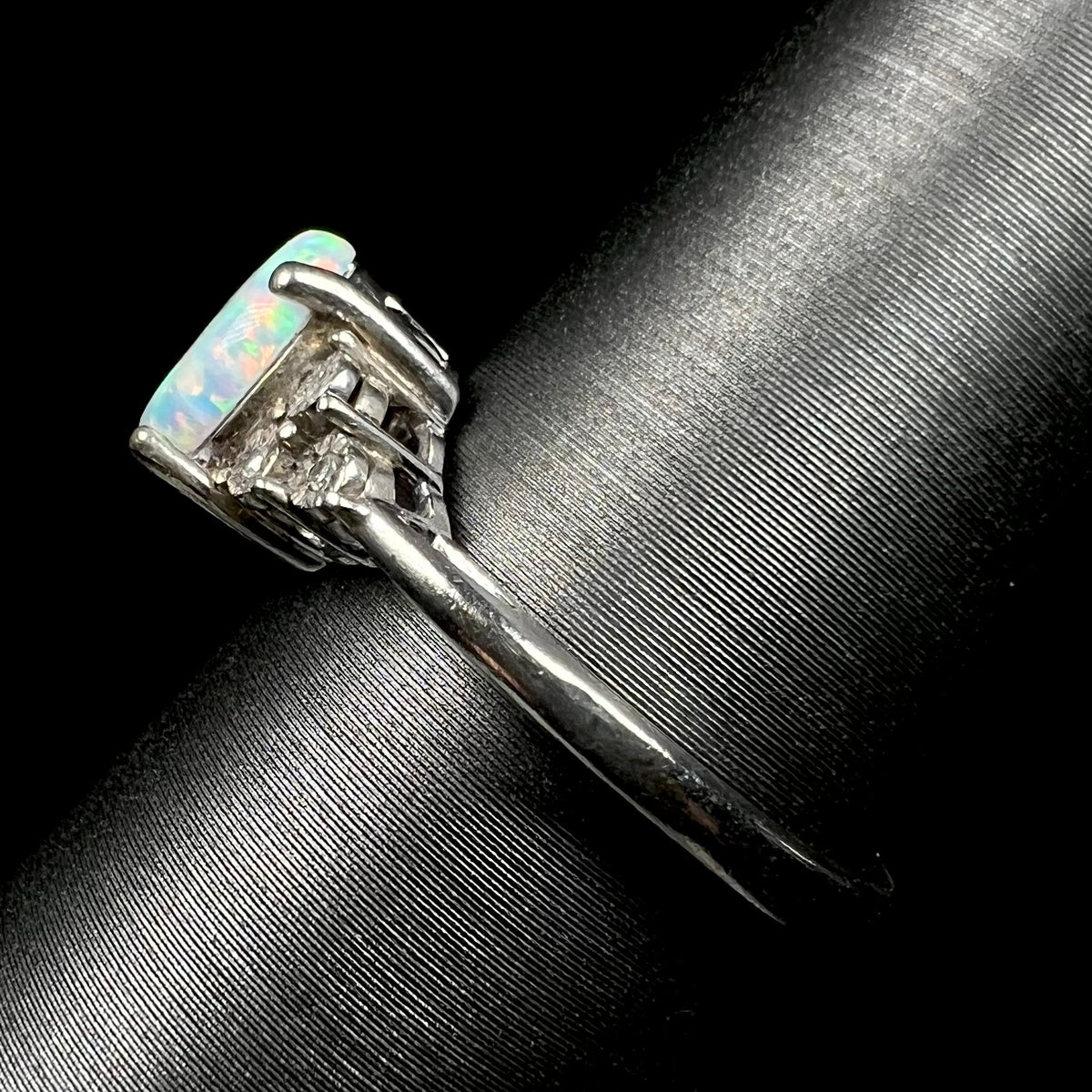 Side shank view of women's estate sterling silver opal ring, shown on ring display.  The shank has light wear.