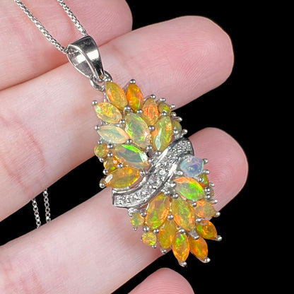Angled close-up of a women's Ethiopian fire opal and white zircon necklace; the faceted marquise and round cut opals are clustered in two separate sections.