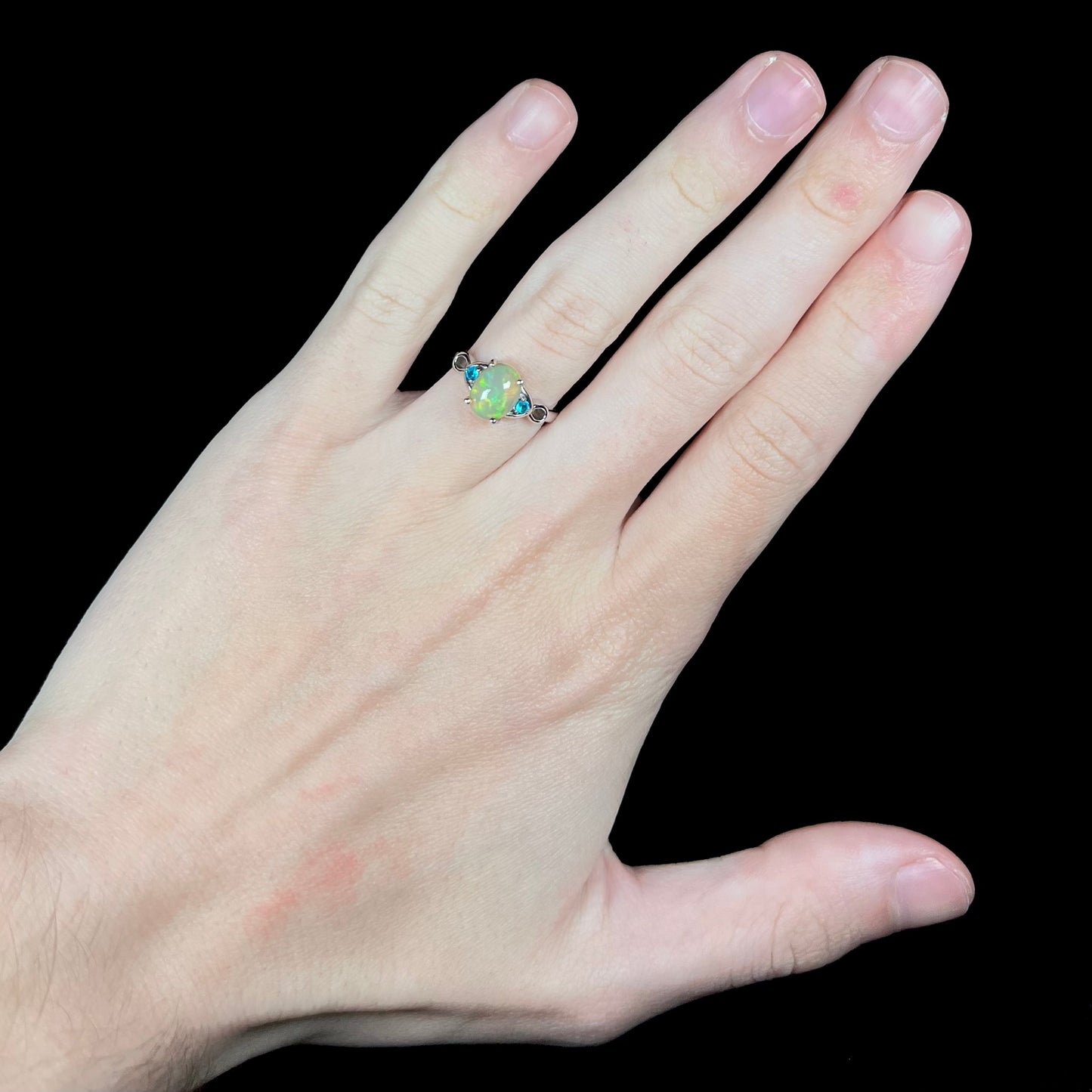 Hand wearing women's sterling silver Ethiopian opal and blue apatite ring