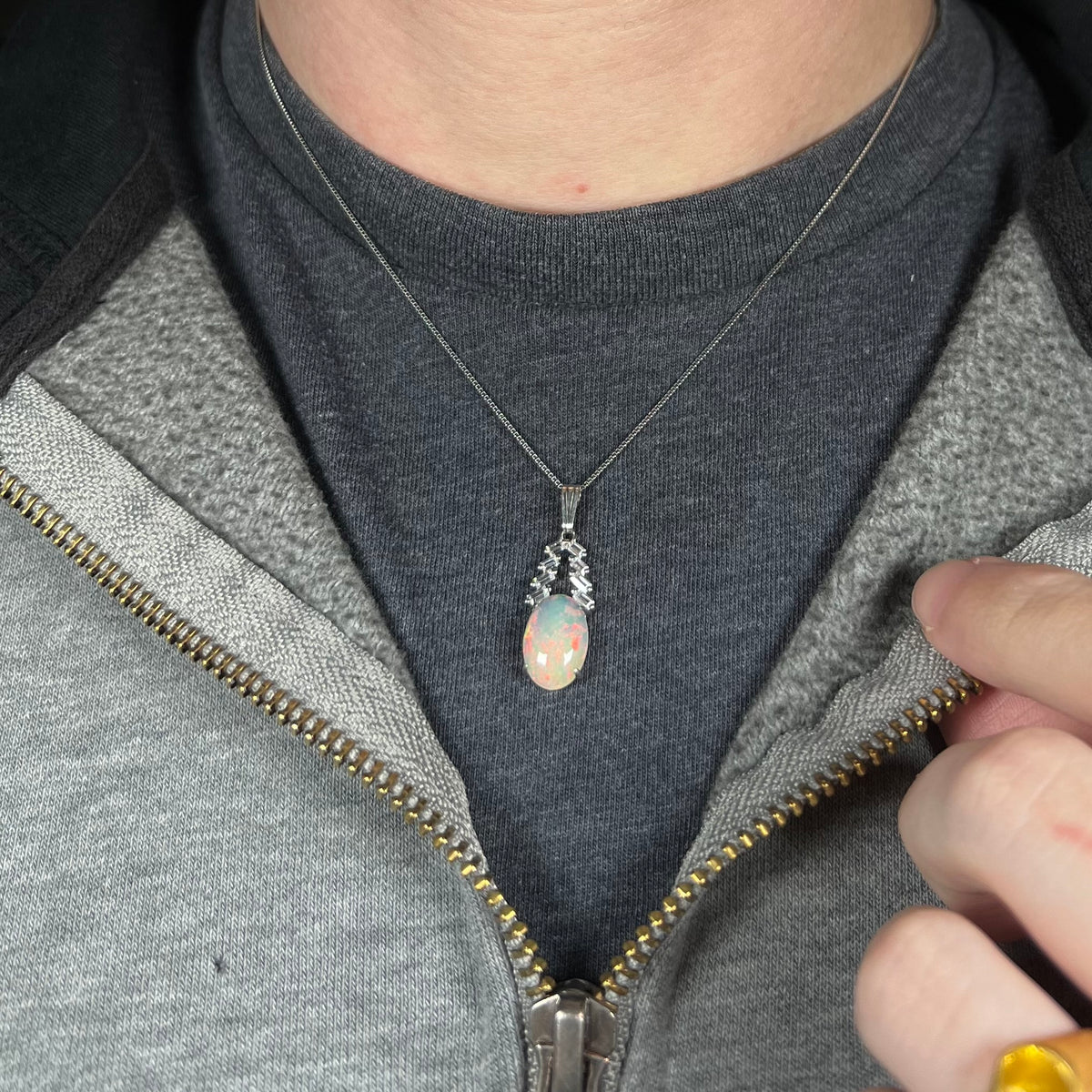 Close-up of person's neck and chest wearing women's sterling silver Ethiopian opal and CZ drop necklace