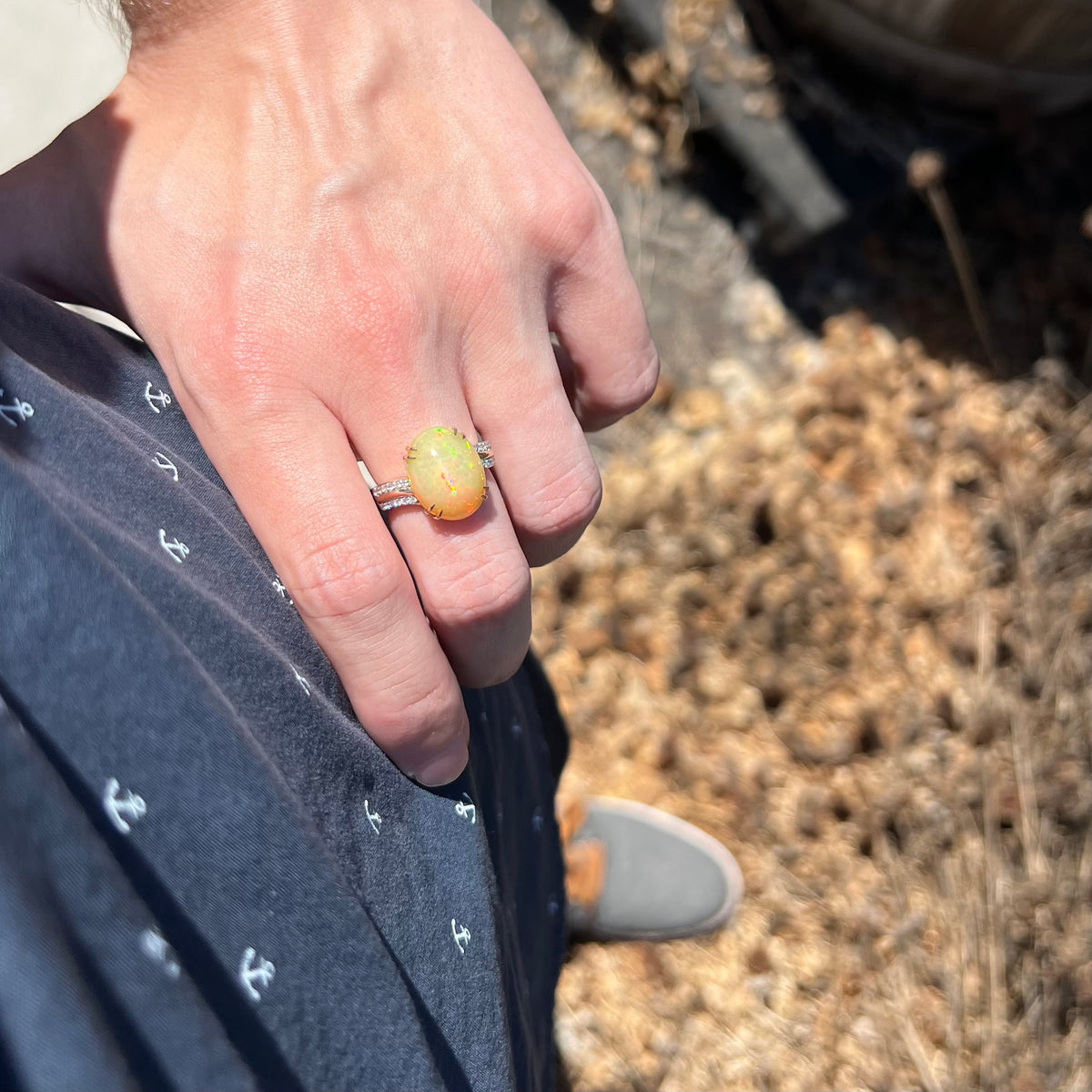 Person's hand resting on hip in sunlight wearing a women's Ethiopian opal and diamond ring