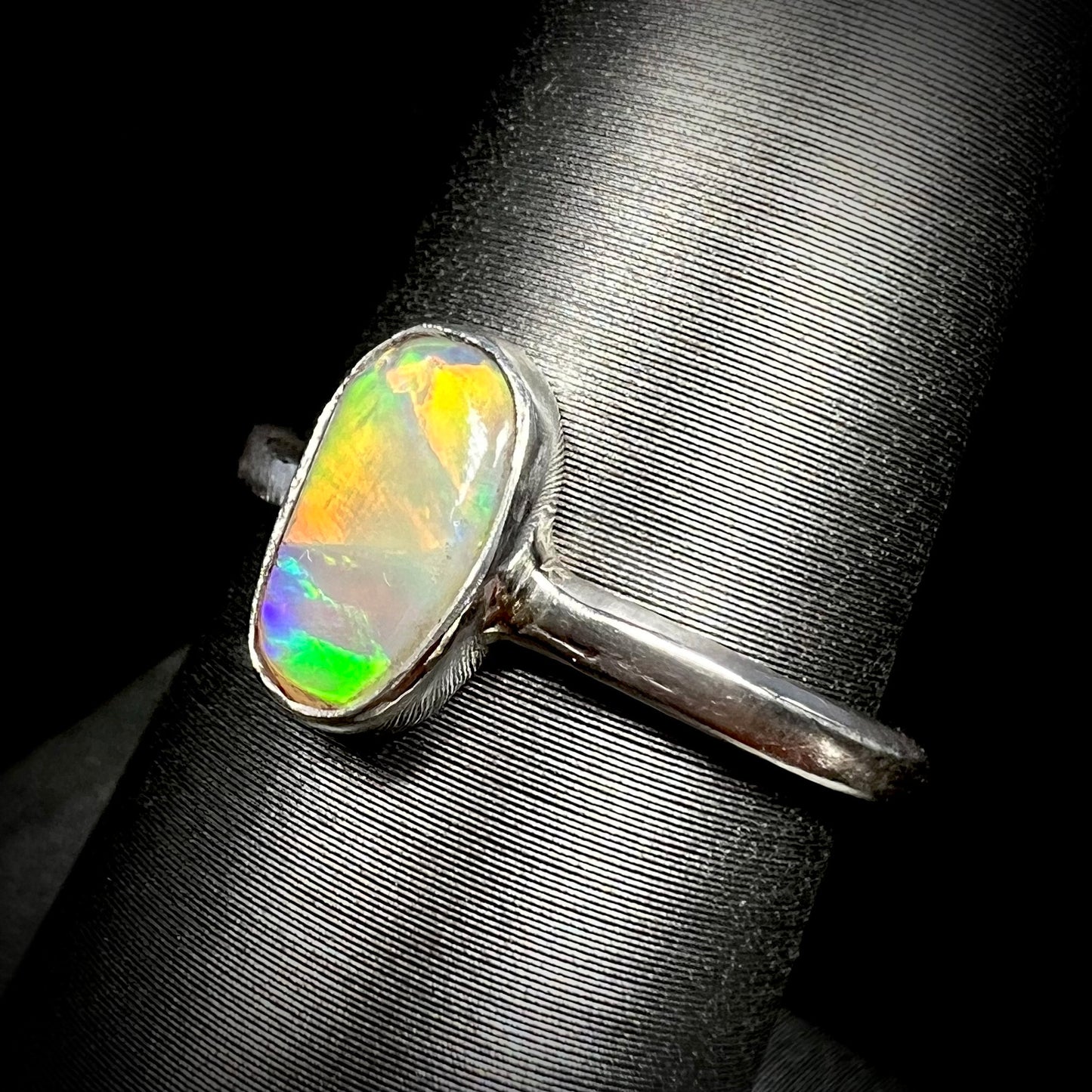 Orange flashes are visible in a women's sterling silver Lightning Ridge crystal opal solitaire ring, shown from an angle on a ring display.