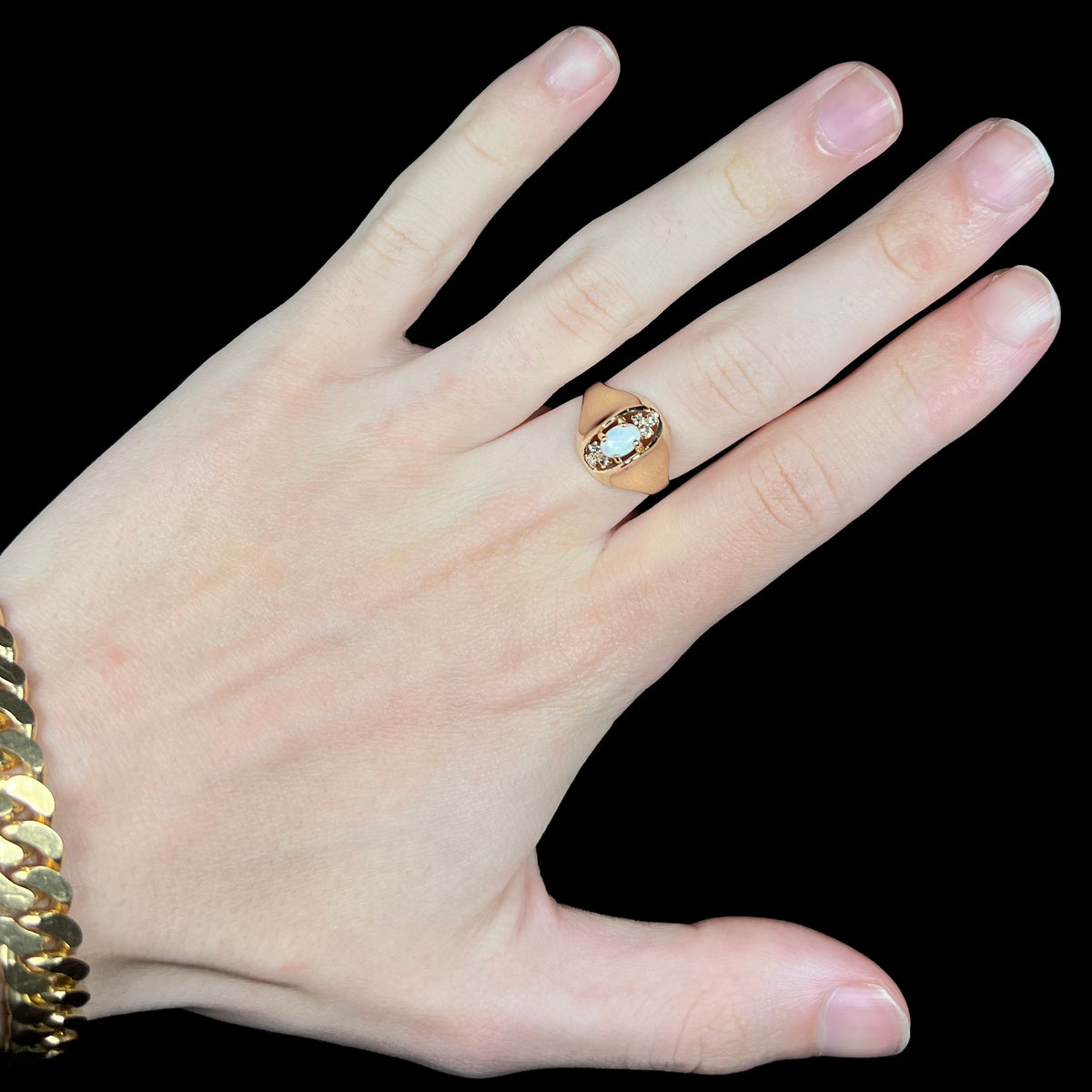 Hand wearing an American Mid-Century style 14k gold women's ring featuring domed design, set with Australian opal flanked by three round diamonds above and below it