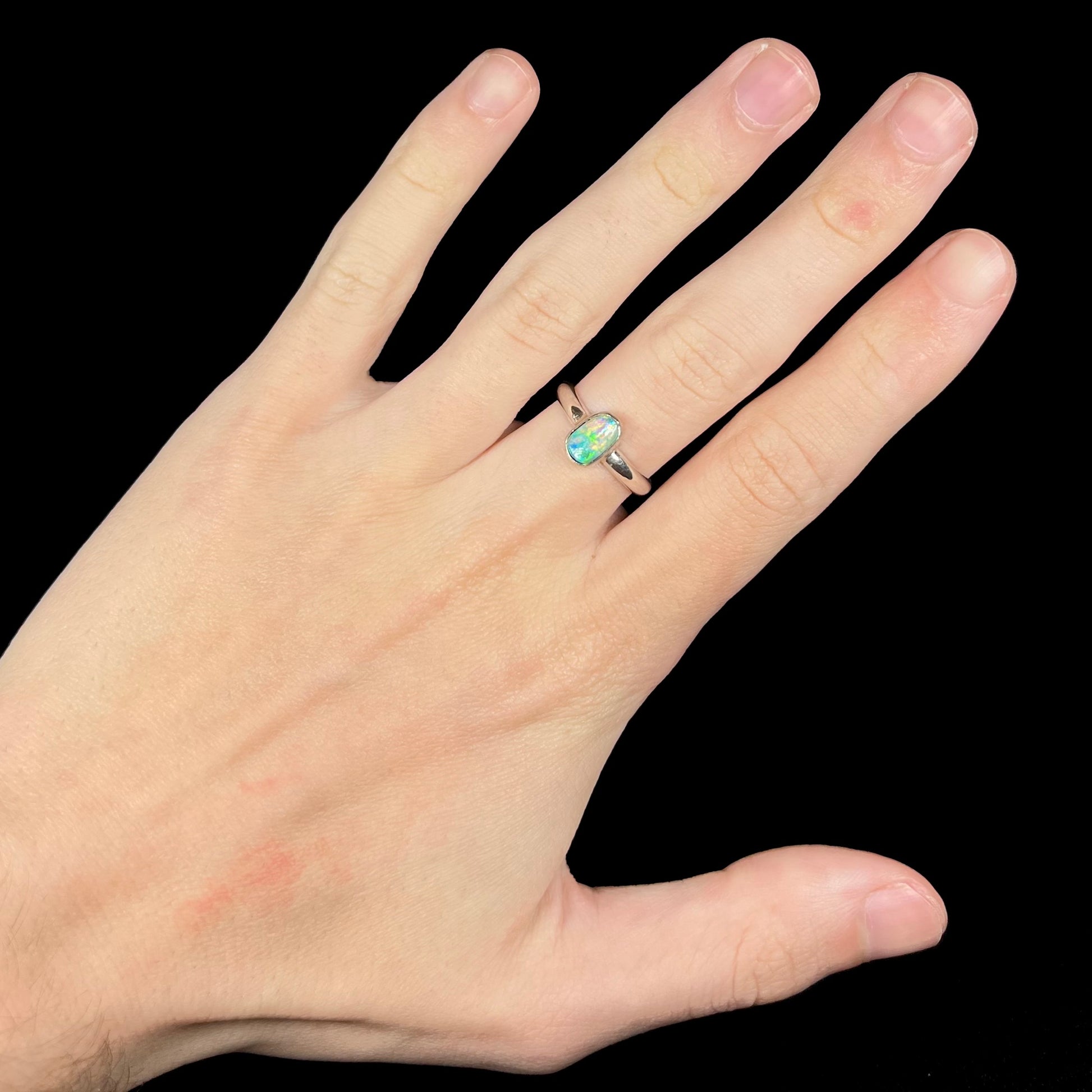 Hand wearing women's natural Australian crystal opal solitaire ring in silver
