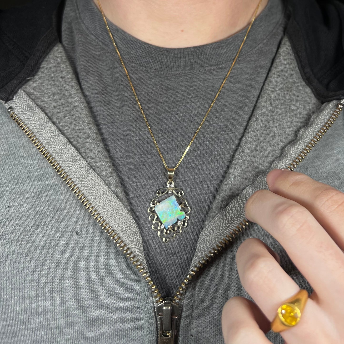 Close-up of person wearing a vintage women's gold opal and diamond fish design necklace around neck