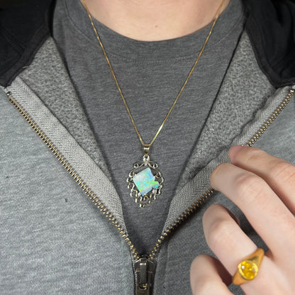 Close-up of person wearing a vintage women's gold opal and diamond fish design necklace around neck