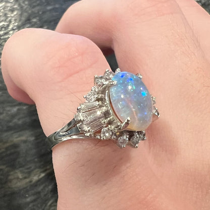 Angled close-up of women's Japanese platinum ring with diamond accents featuring an Australian opal that is subtle blue in appearance due to low-lighting