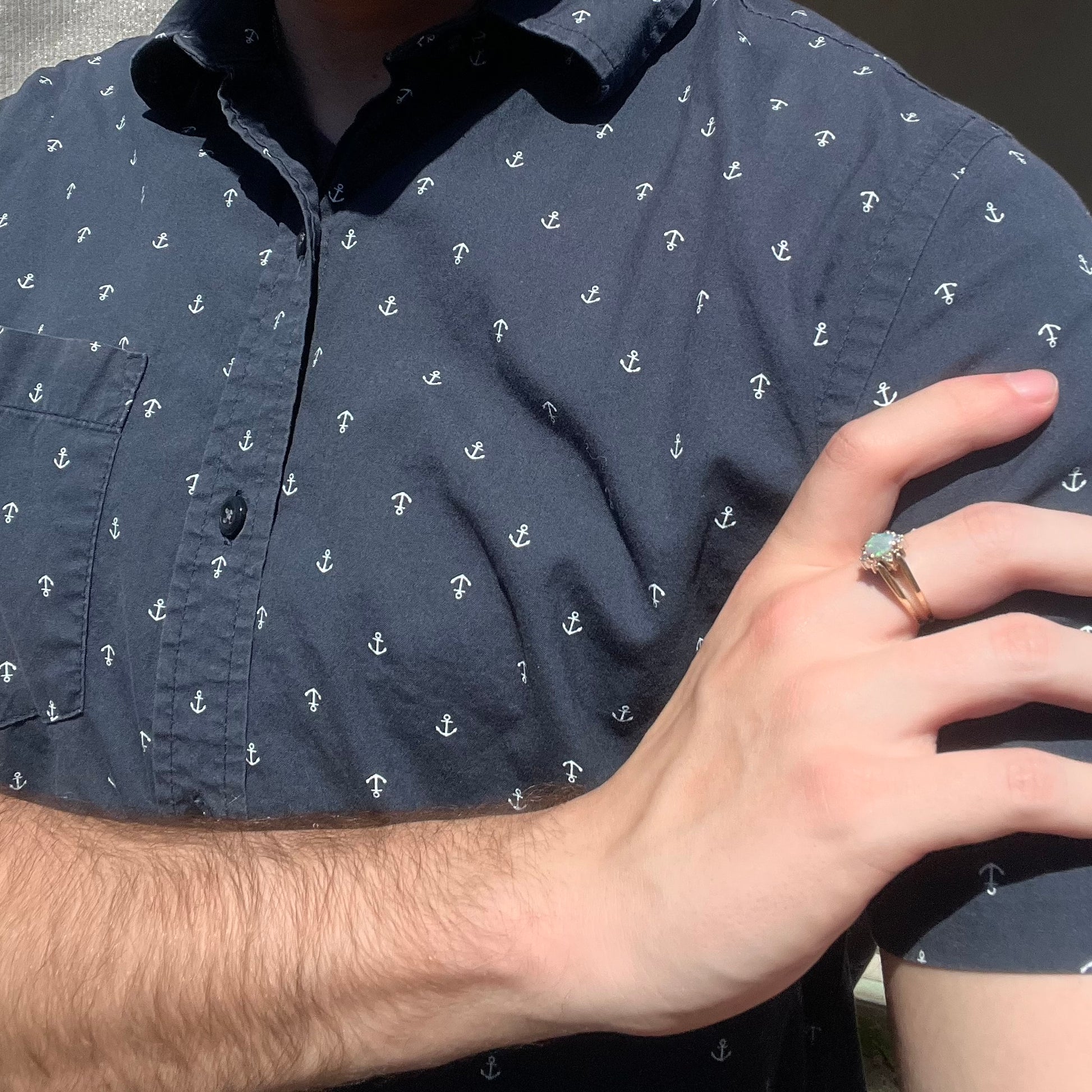 Close-up of person resting hand on shoulder in sunlight while wearing women's reversible gold opal and diamond flip ring