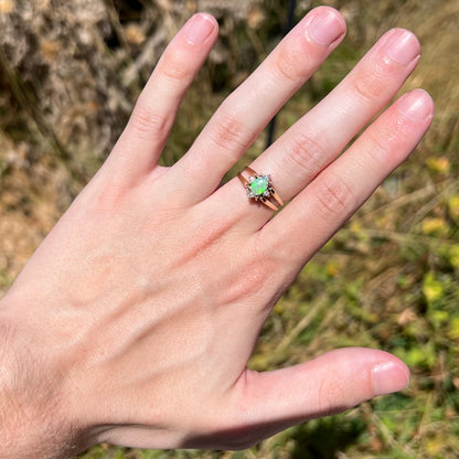 Hand wearing women's reversible gold opal and diamond ring in sunlight