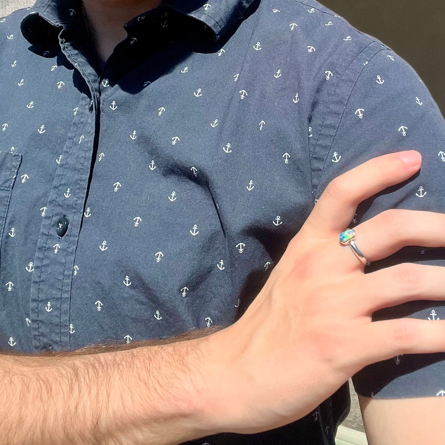 Person resting hand on shoulder while wearing silver women's Australian crystal opal solitaire ring in sunlight