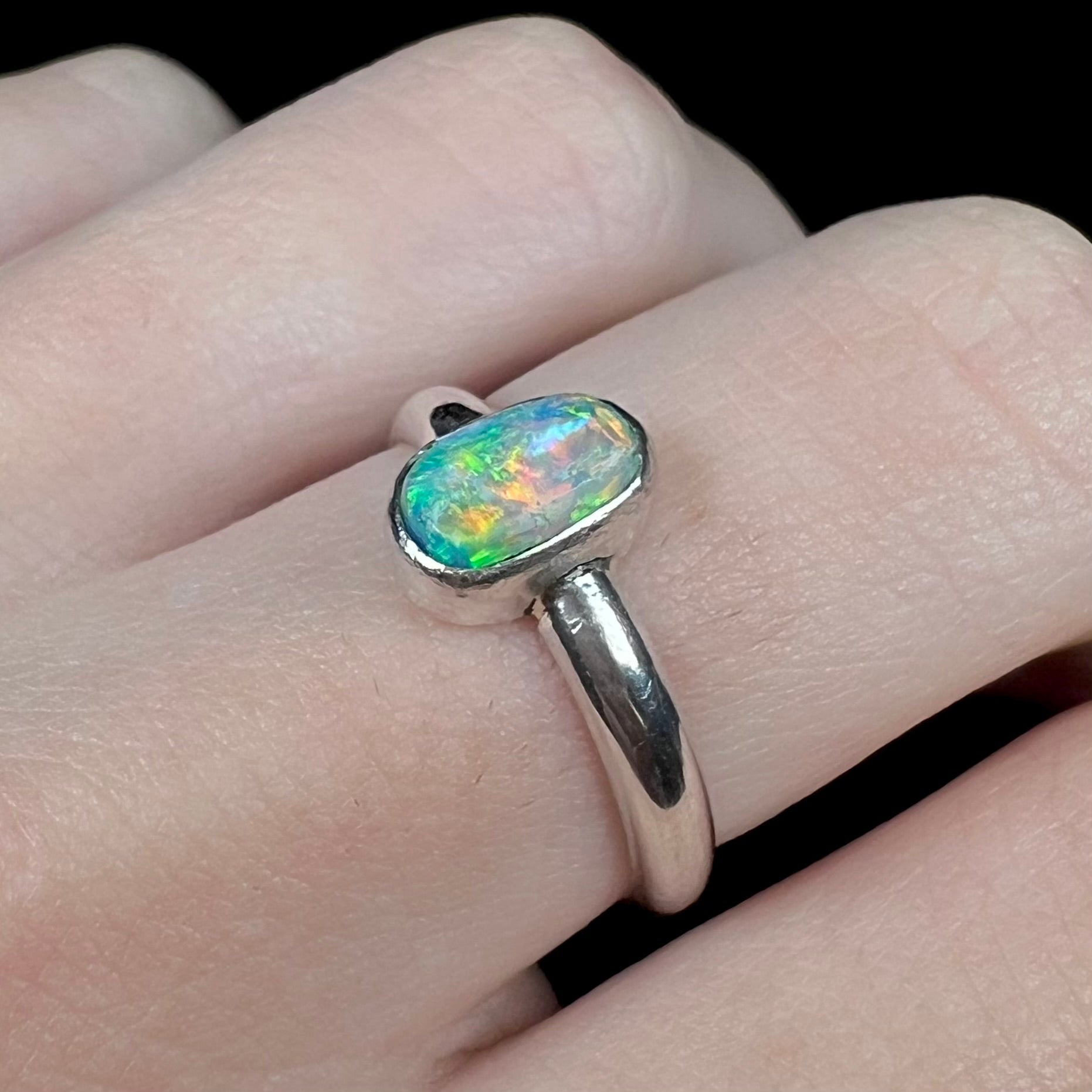 Orange flashes seen in women's silver Australian crystal opal ring, worn on finger