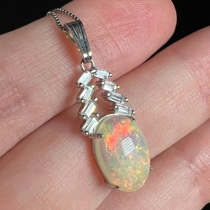 Women's silver Ethiopian opal and cubic zirconia pendant shown close-up in hand