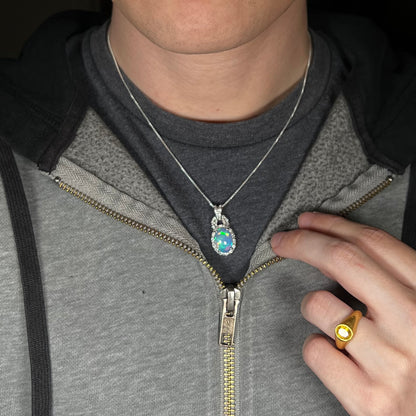 Close-up of person wearing women's sterling silver Ethiopian opal halo design necklace around neck