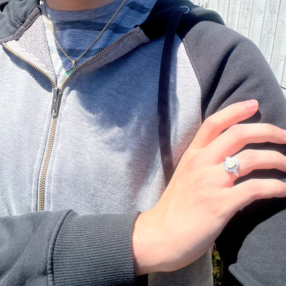 Close-up of person resting hand on opposing shoulder in sunlight wearing women's silver Ethiopian opal ring