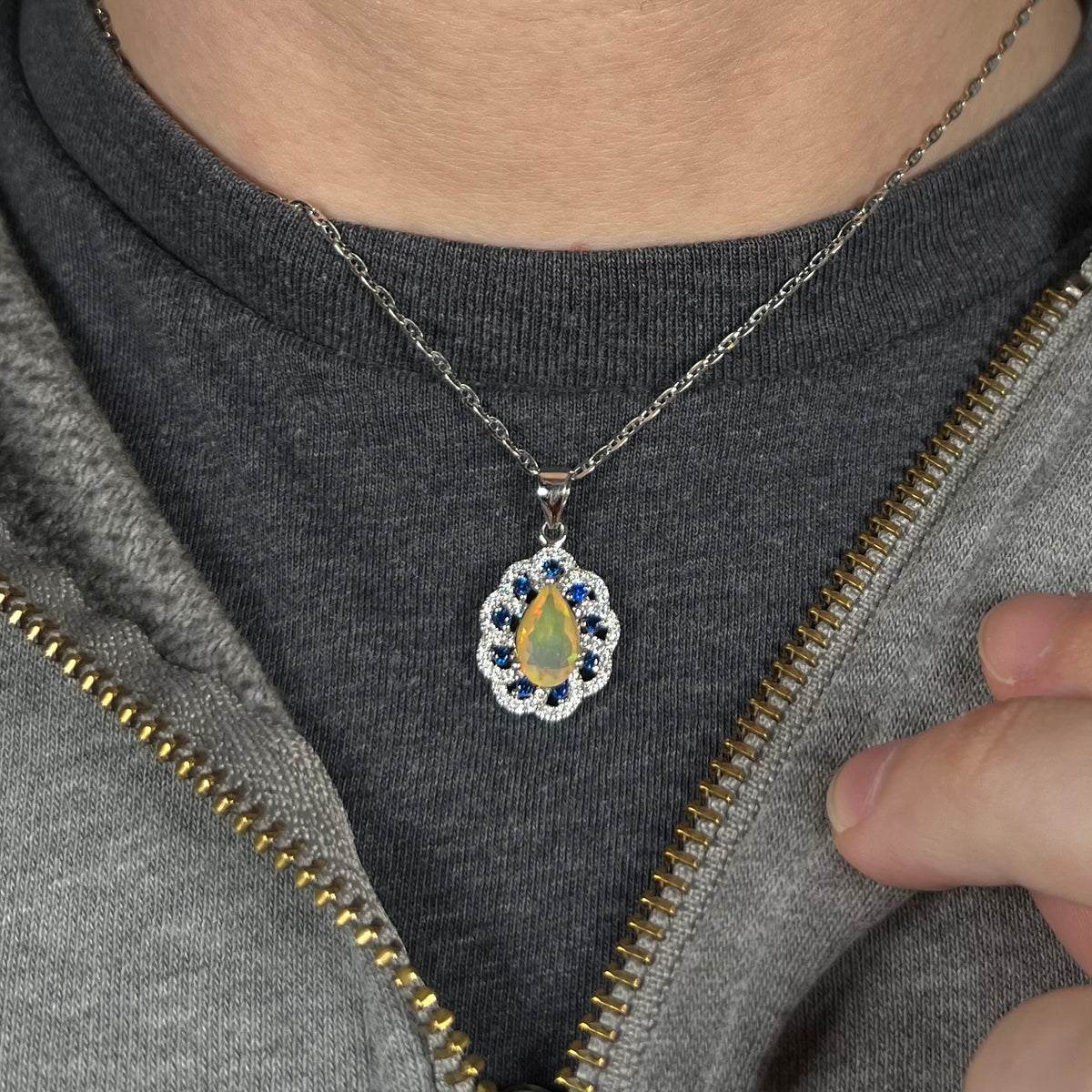 Delicate silver women's necklace set with teardrop shaped Ethiopian opal and blue sapphires, worn around person's neck