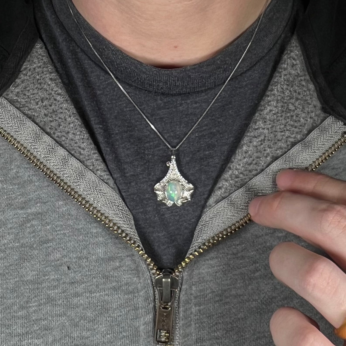 Close-up of person's neck and chest wearing women's sterling silver ginko leaf necklace set with Ethiopian opal