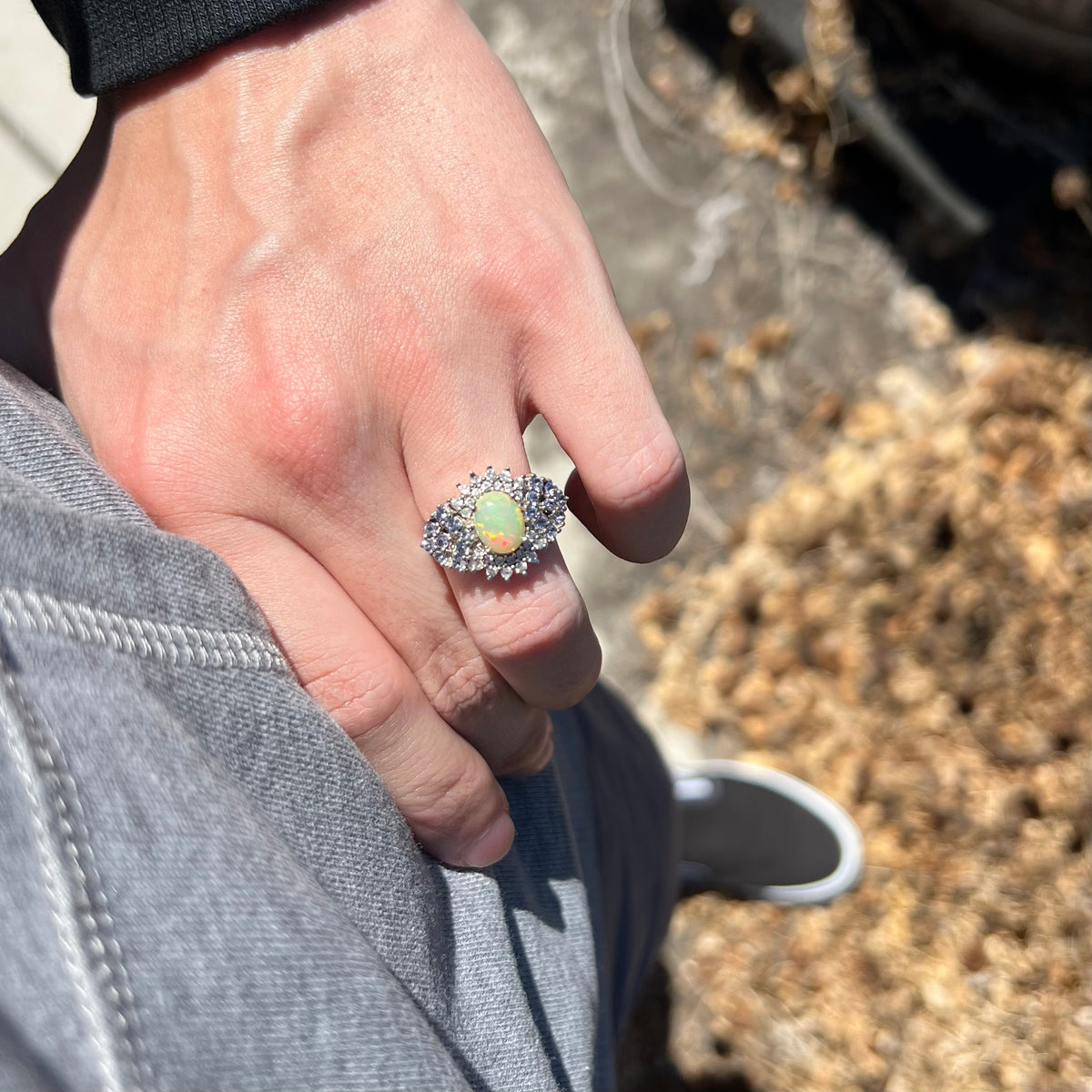 Person's hand resting on hip in sunlight wearing women's sterling silver Ethiopian opal and multi-gemstone cluster ring