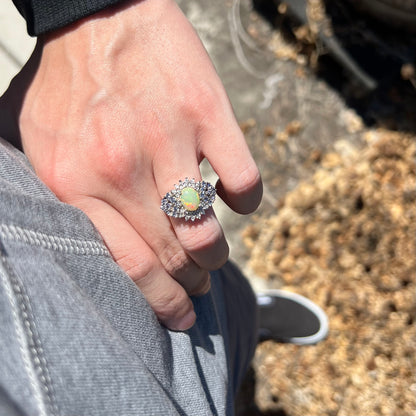 Person's hand resting on hip in sunlight wearing women's sterling silver Ethiopian opal and multi-gemstone cluster ring
