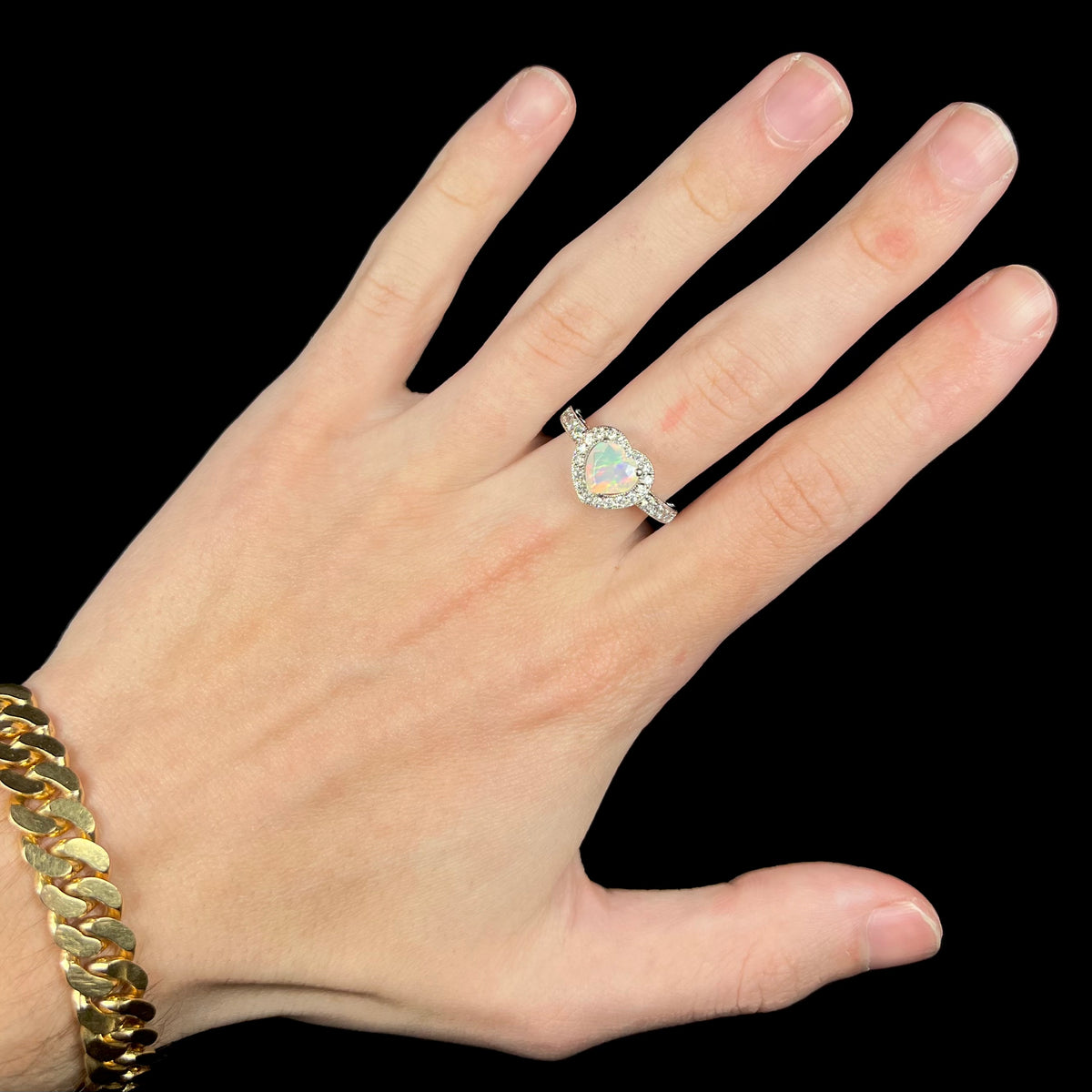 Hand wearing women's sterling silver heart cut opal ring with halo design