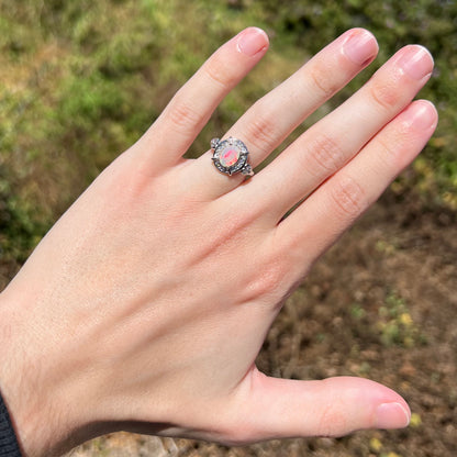 Hand wearing women's sterling silver Ethiopian opal ring with red flash of color in natural sunlight