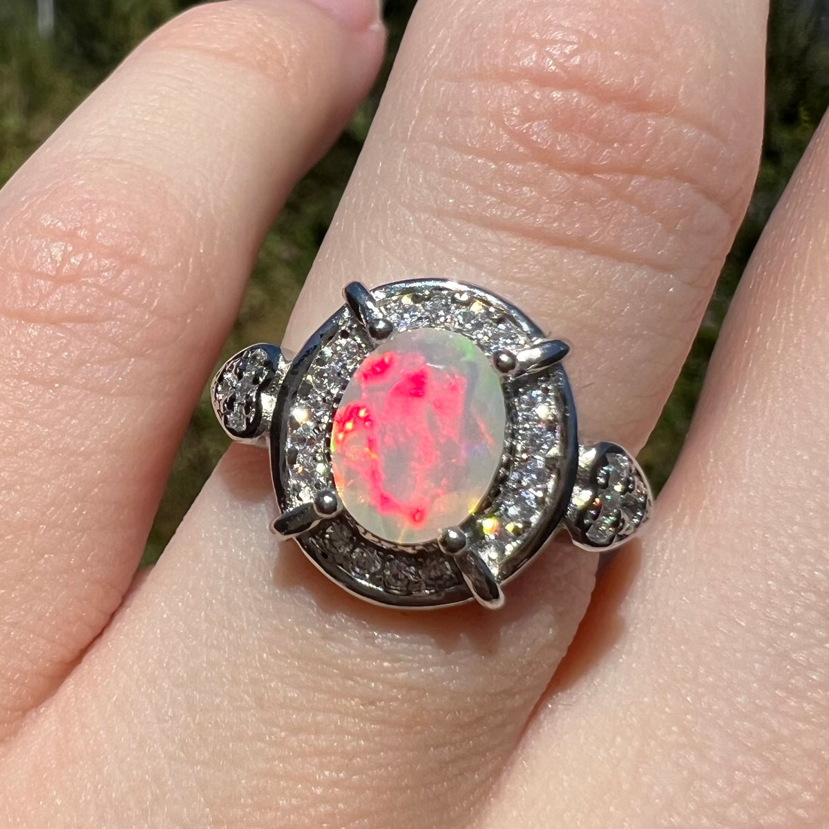 Bright red flash seen in faceted oval cut Ethiopian opal sterling silver women's ring, worn on finger in sunlight