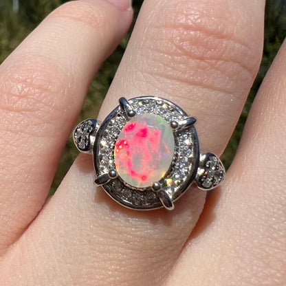 Bright red flash seen in faceted oval cut Ethiopian opal sterling silver women's ring, worn on finger in sunlight