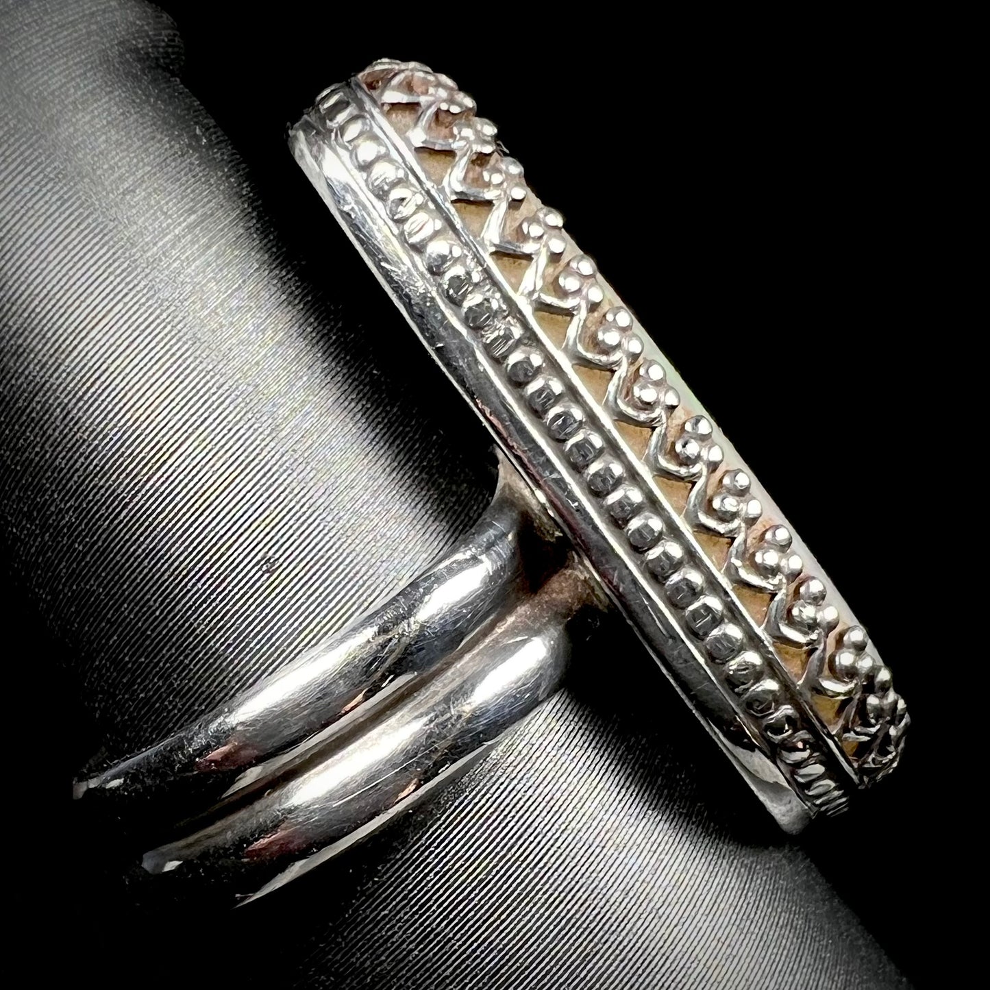The side view of a women's sterling silver crown design opal ring, shown close-up on a ring display.