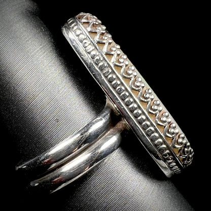 The side view of a women's sterling silver crown design opal ring, shown close-up on a ring display.