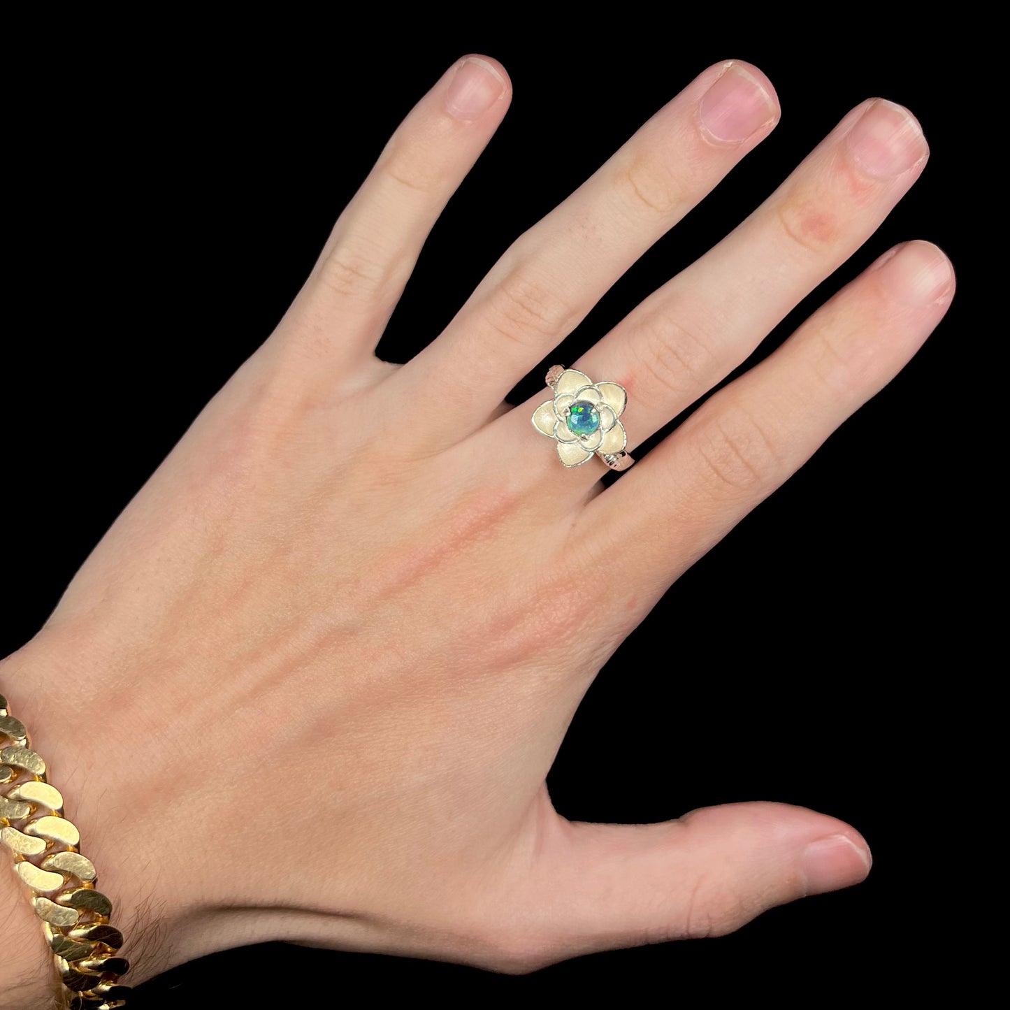 Hand wearing women's sterling silver lotus flower ring set with round black opal stone
