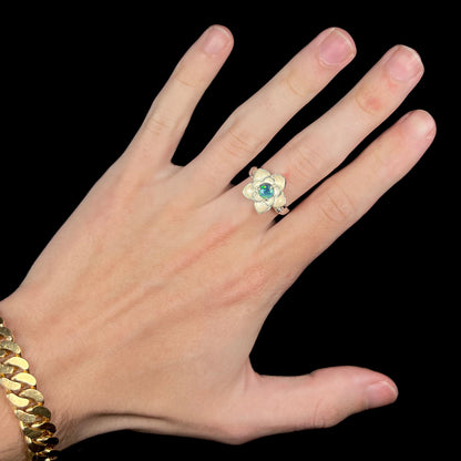 Hand wearing women's sterling silver lotus flower ring set with round black opal stone