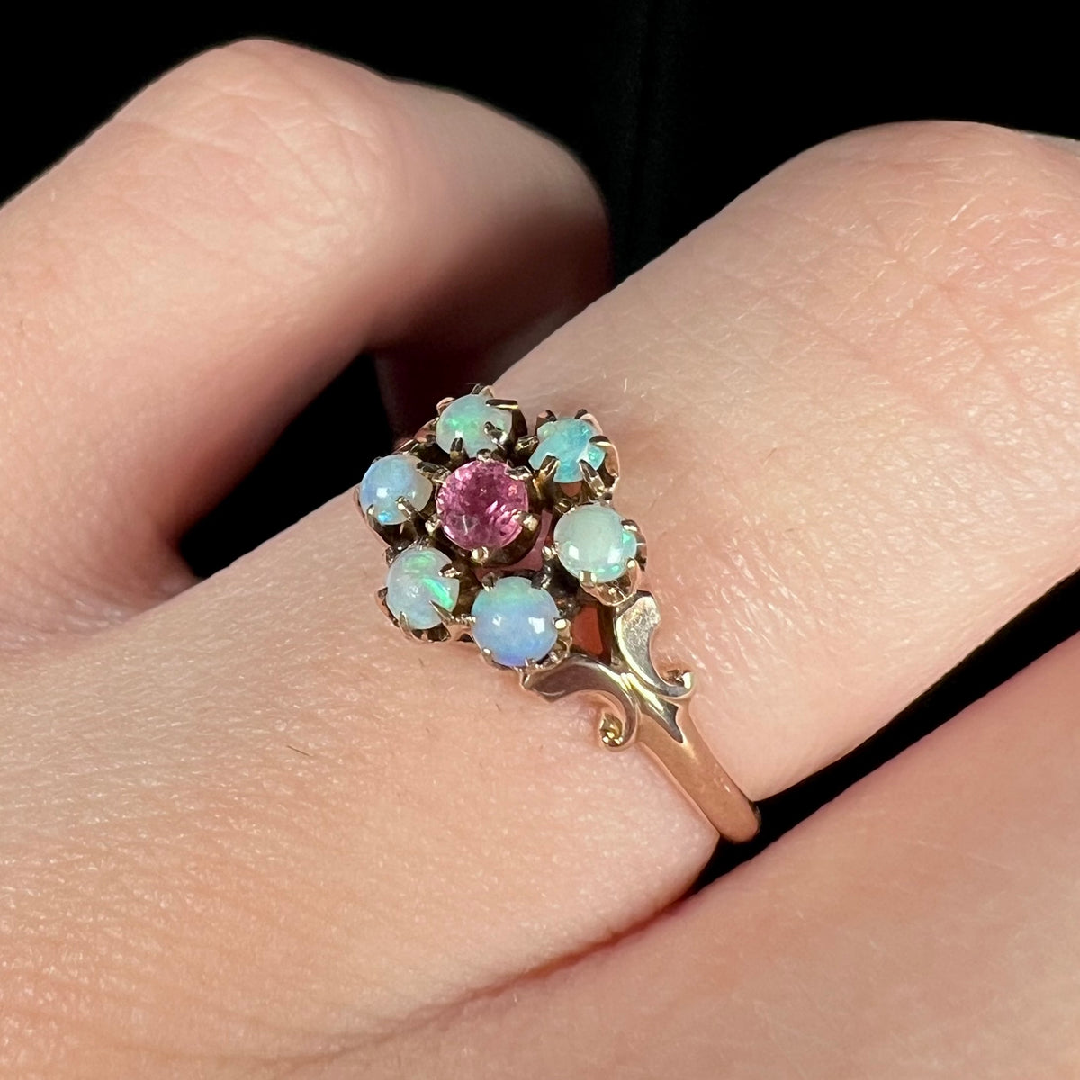 Women's Victorian opal and pink tourmaline ring in 9k gold, shown close-up from angle on finger