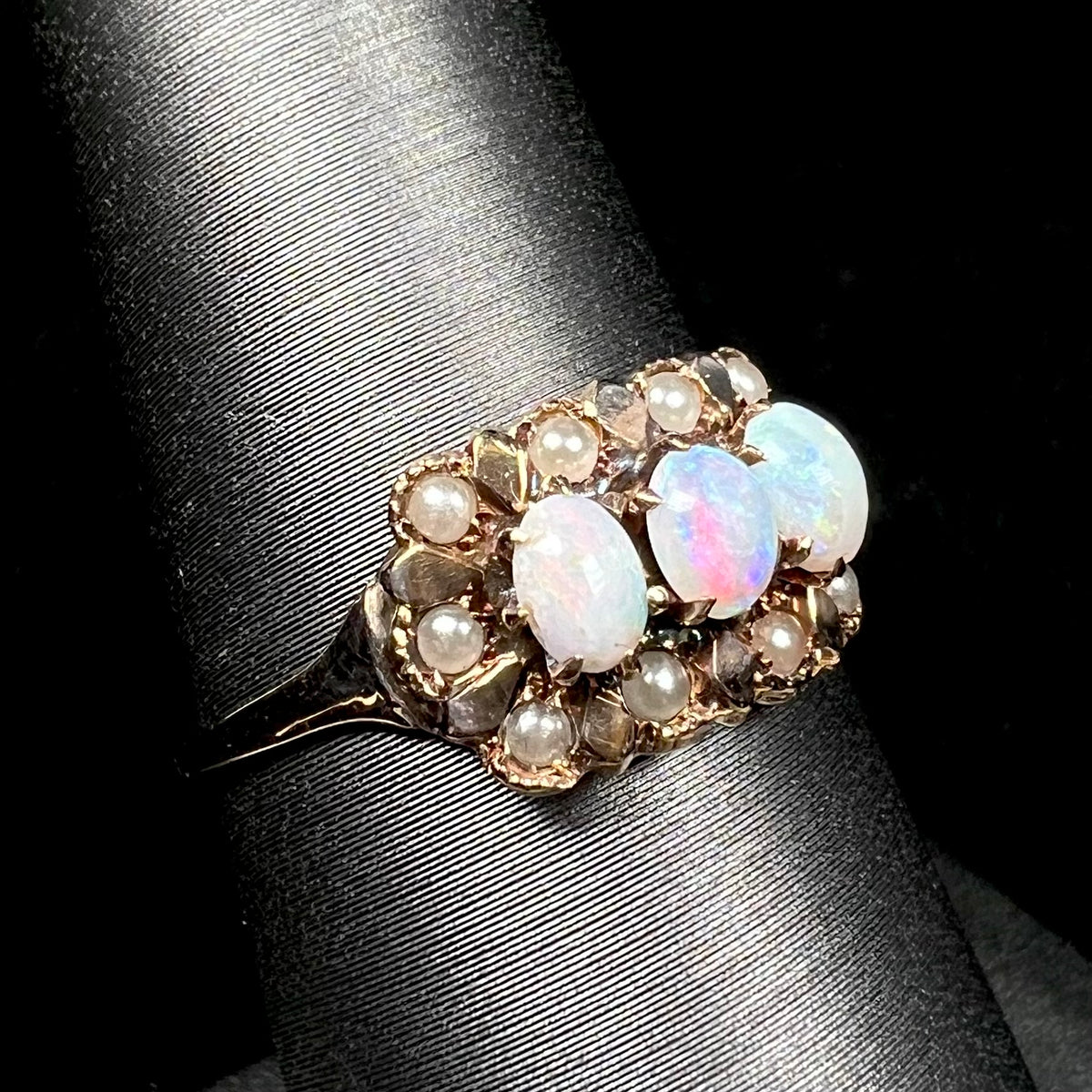 Women's 19th century Victorian opal and seed pearl ring in 9k gold, shown from angle on ring display