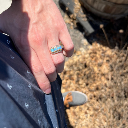 Person's hand resting on hip in sunlight wearing women's gold Victorian opal and seed pearl ring