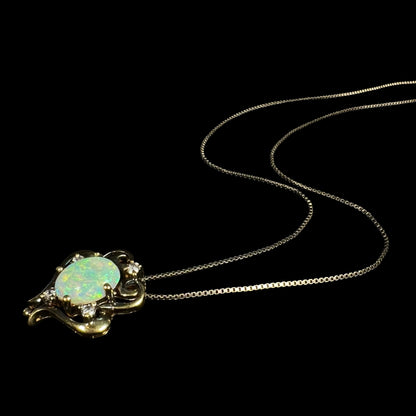 Angled view of a women's Victorian-style lab-created opal and cubic zirconia necklace laying on a black background, its silver chain trailing behind it.