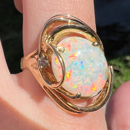 Bright red play-of-color seen with blue flashes across large Australian opal mounted in vintage 14k gold women's cocktail ring
